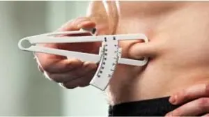 Abdomem masculino com adipometro na dobra suprailíaca