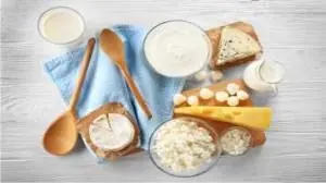 leite, queijo branco, queijo amarelos, iogurte, em recipiente separados em cima da mesa