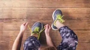 Moça amarrando o tênis com roupa de academia