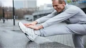 Homem meia idade de moletom cinza alongando para correr