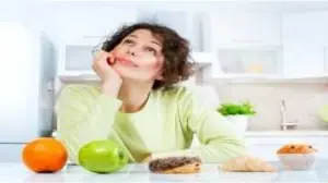 Mitos e verdades sobre emagrecimento, mulher em dúvida com alimentos sobre a mesa