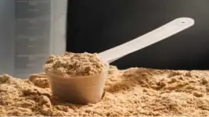 Colher medida com whey protein de chocolate em pó