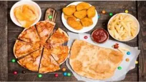 pizza, pastel, catchup, nuggets, fritas e balas dispostas sobre a mesa