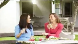 Duas mulher à mesa comendo e bebendo