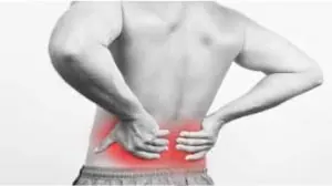 Costas de um homem levando a mão na lombar com dor. Imagem em preto e branco, na região da dor em vermelho