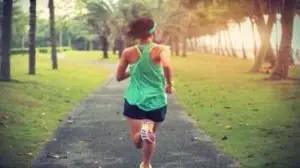 moça de costas correndo em pista ao ar livre de blusa verce