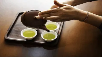mão feminina porcionando chá em copinhos plasticos, alimentos que emagrecem