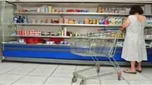 Mulher de costas escolhendo alimentos no refrigerador do supermercado